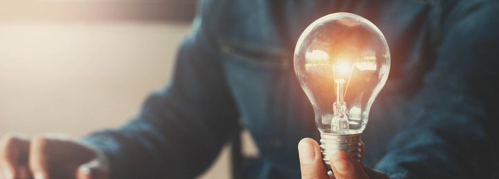 Man holding lit light bulb in left hand